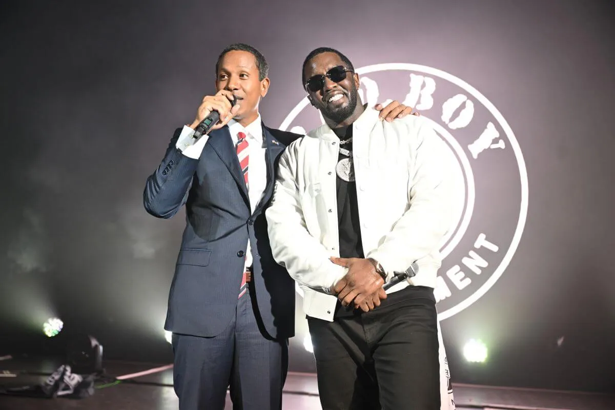 Moses 'Shyne' Barrow talks into a microphone and stands with his arm on Sean 'Diddy' Combs' shoulder.