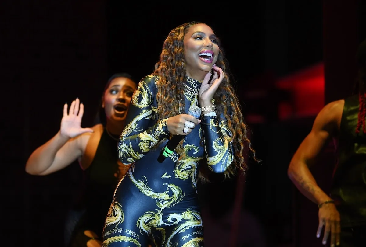 Wearing a Versace bodysuit, singer Tamar Braxton performs onstage in 2024