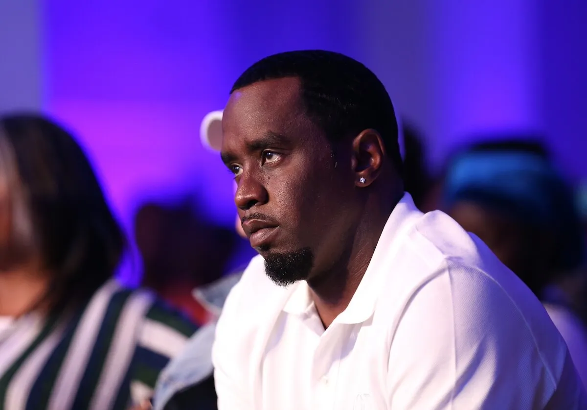 A side profile of Sean 'Diddy' Combs looking solemn against a purple background