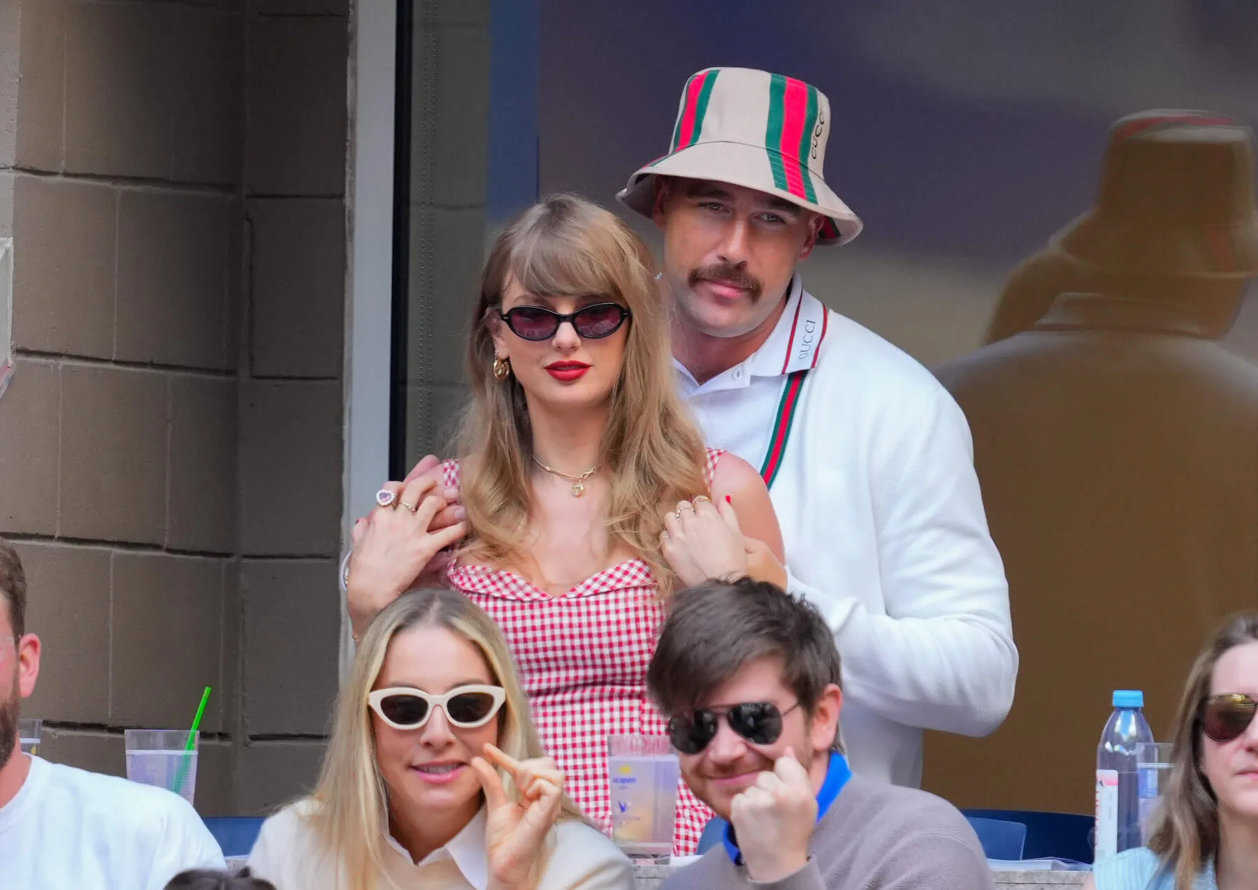 Travis Kelce standing slightly behind Taylor Swift with his hands on her shoulders at the US Open in September 2024