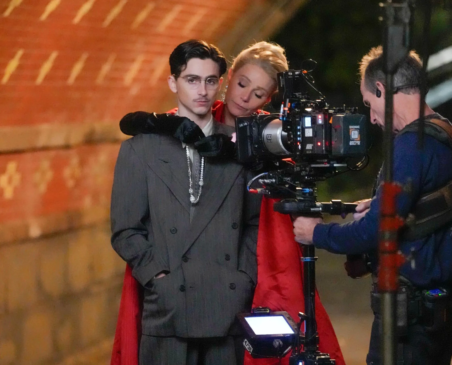 Gwyneth Paltrow and Timothée Chalamet on the set of 'Marty Supreme.' Paltrow is behind Chalamet with her arms around his shoulders.