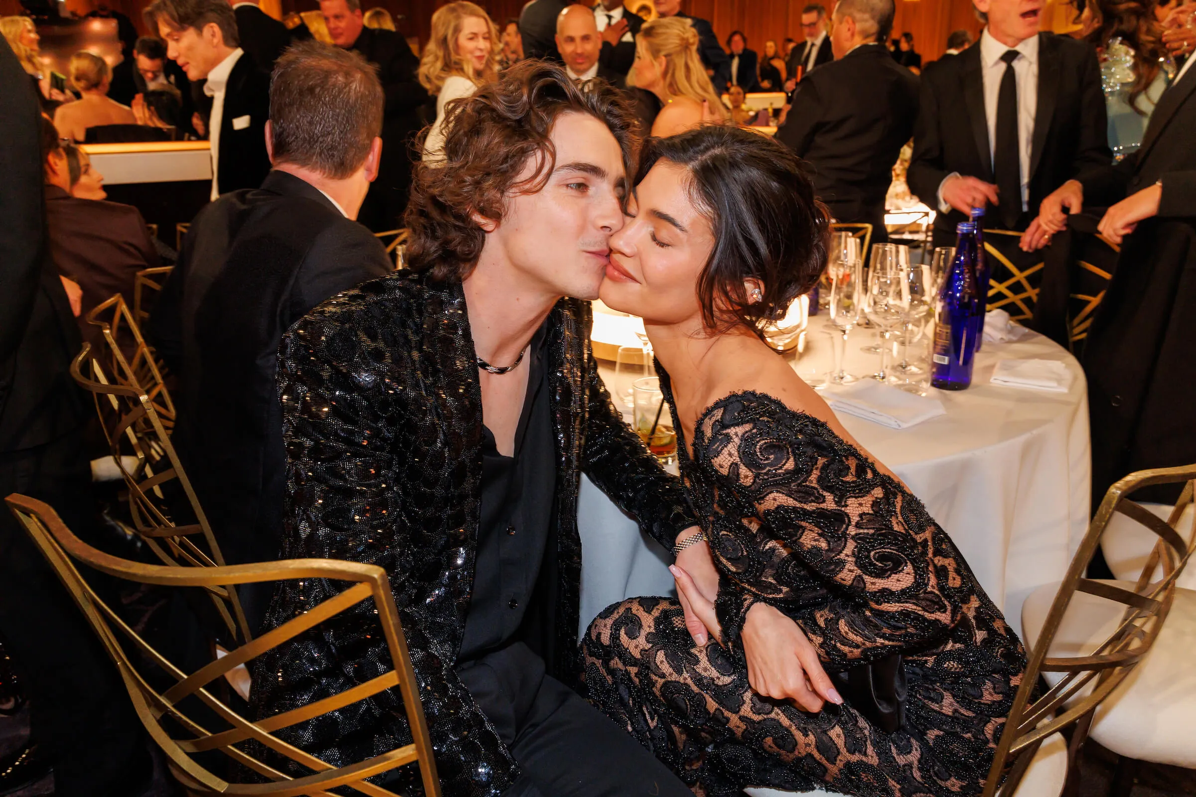 Timothée Chalamet kissing Kylie Jenner on the cheek while sitting at a table at the 81st Golden Globe Awards