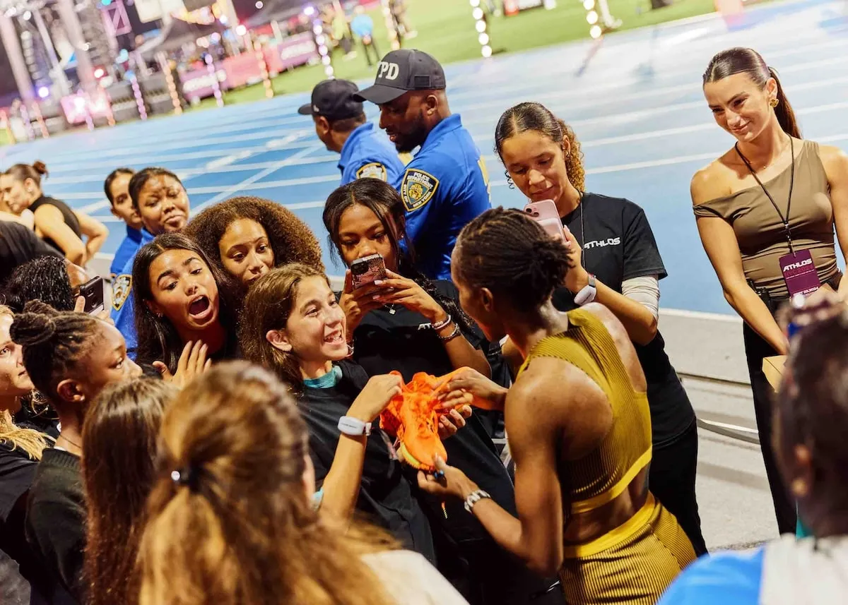 Faith Kipyegon signs her spikes for a fan after winning the 1500m race at the Athlos