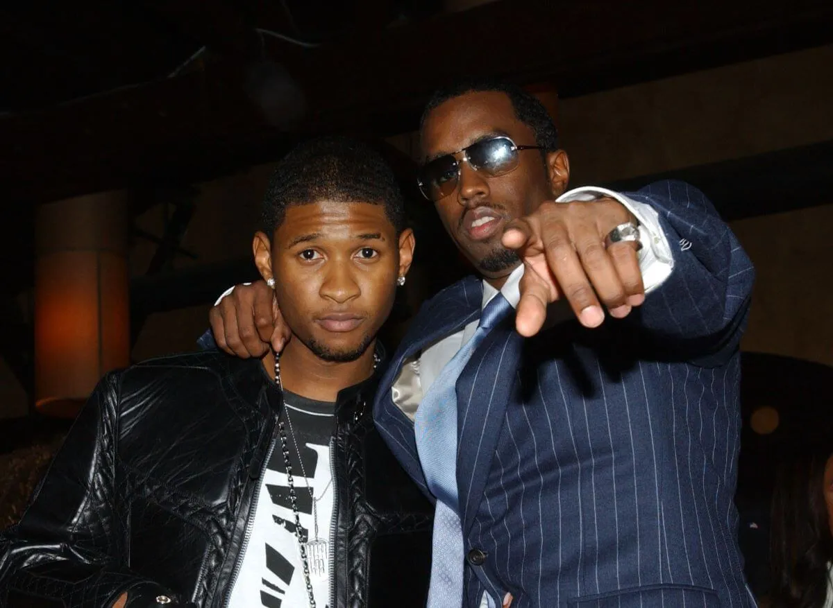 Sean 'Diddy' Combs points at the camera and stands with his arm around Usher's shoulders.