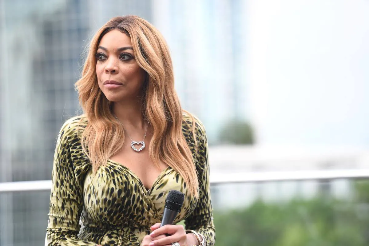 Wendy Williams wears a green dress and stands outside.