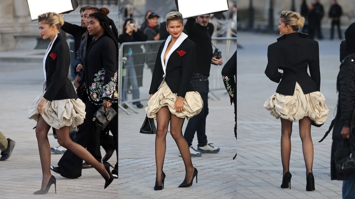 Wearing a black blazer and beige bubble skirt, Zendaya smiles for cameras and walks across the plaza before the Louis Vuitton show