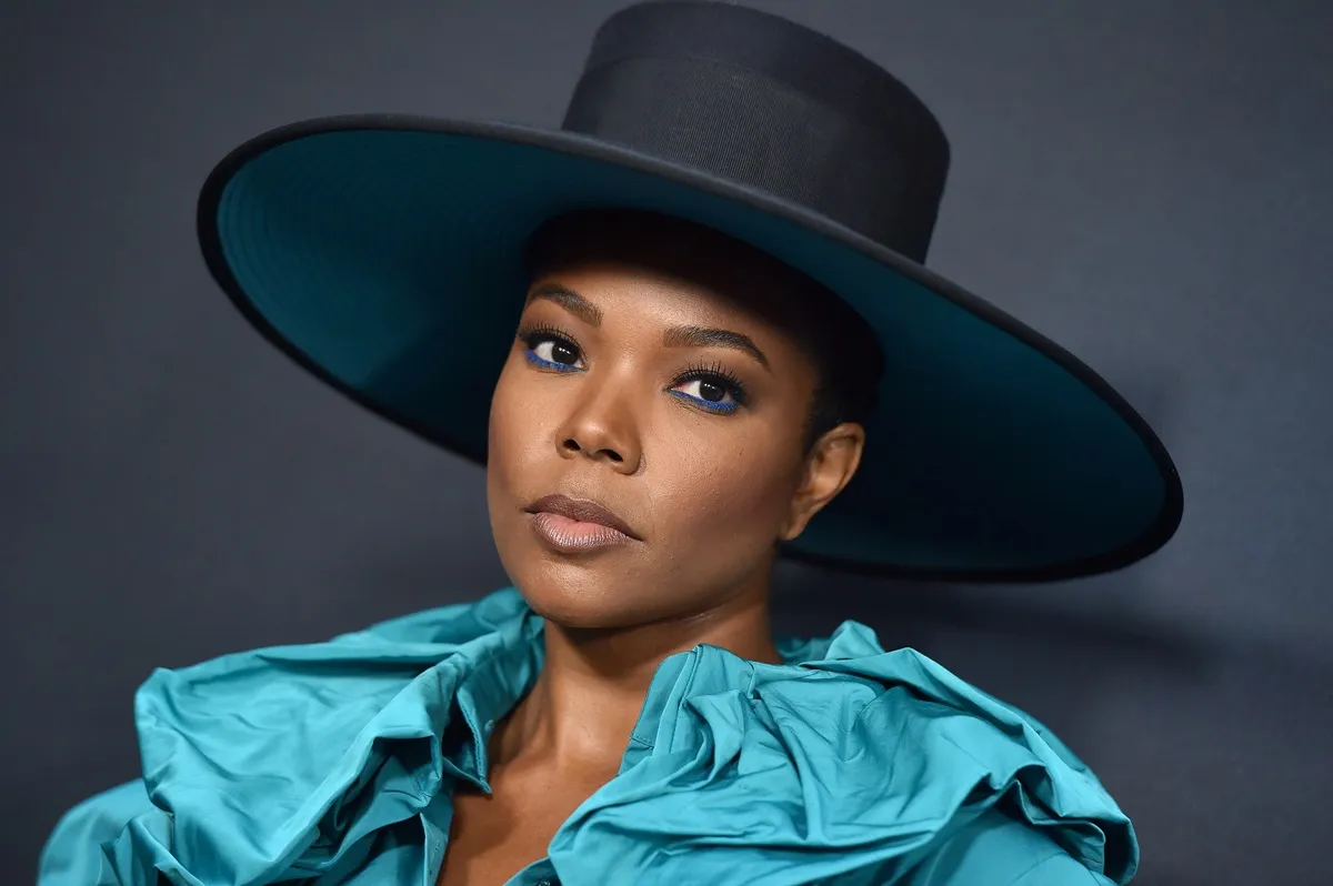 Gabrielle Union posing in a green shirt and black hat at the premiere of 'Breaking In'.