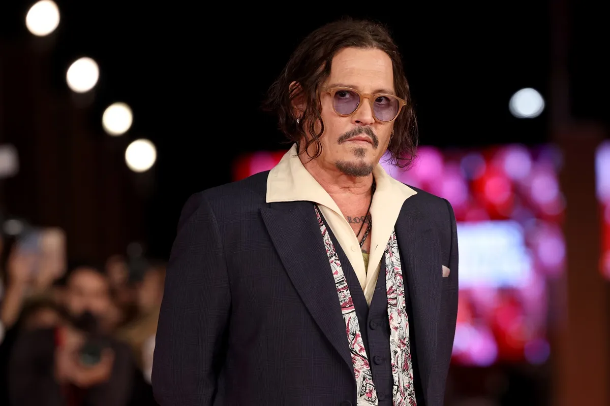 Johnny Depp attends the "Modì – Three Days On The Wing Of Madness" red carpet wearing a black and yellow outfit.