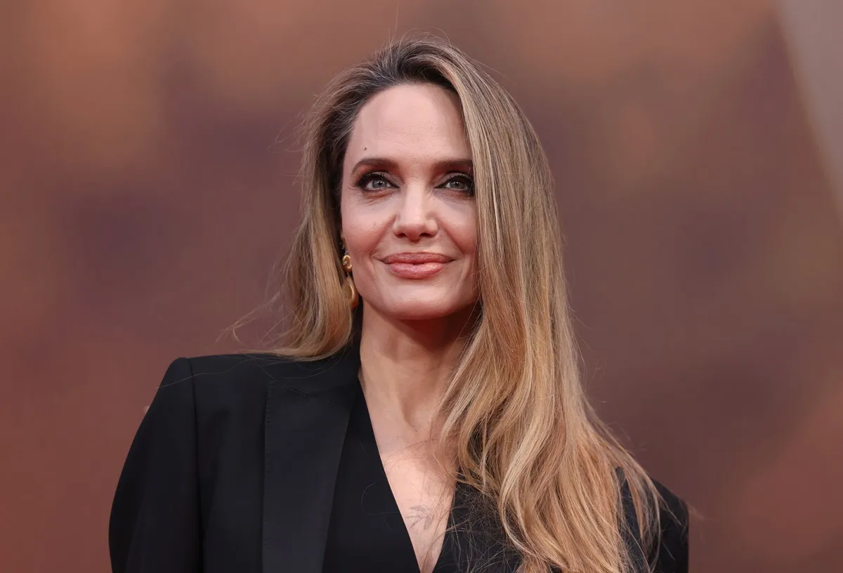 Angelina Jolie smirking at the "Maria" Headline Gala while wearing a black suit.