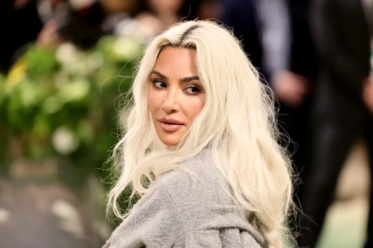 Kim Kardashian looking back over her left shoulder while wearing a silver outfit and blond hair at the 2024 Met Gala 