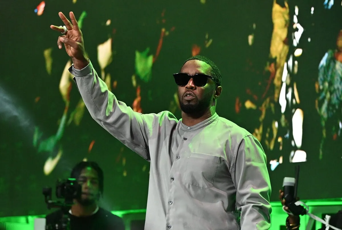 Sean "Diddy" Combs attends Day 1 of 2023 Invest Fest, posing on stage while raising his arm.