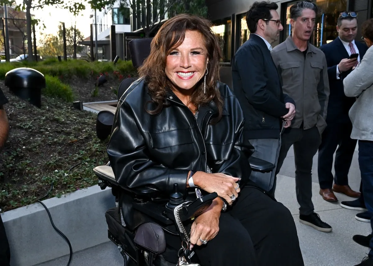 Wearing a black leather jacket, Abby Lee Miller smiles before the premiere of 2024's A Man in Full