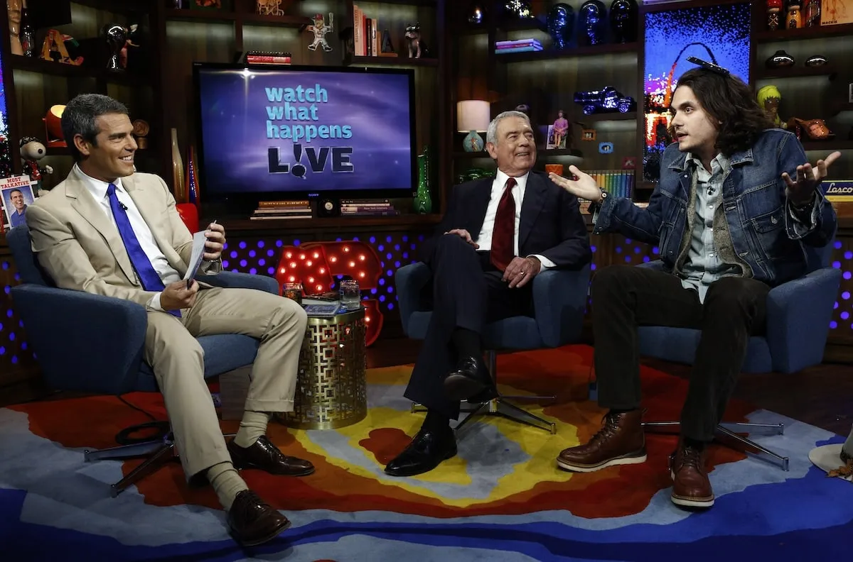 Wearing a brown suit, Andy Cohen interviews Dan Rather and John Mayer on 'Watch What Happens Live' in 2012