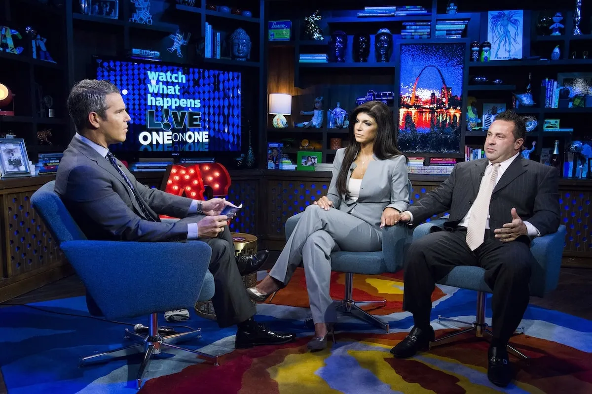 Wearing a gray suit, Andy Cohen interviews Teresa Giudice and Joe Giudice on 'Watch What Happens Live' in 2013