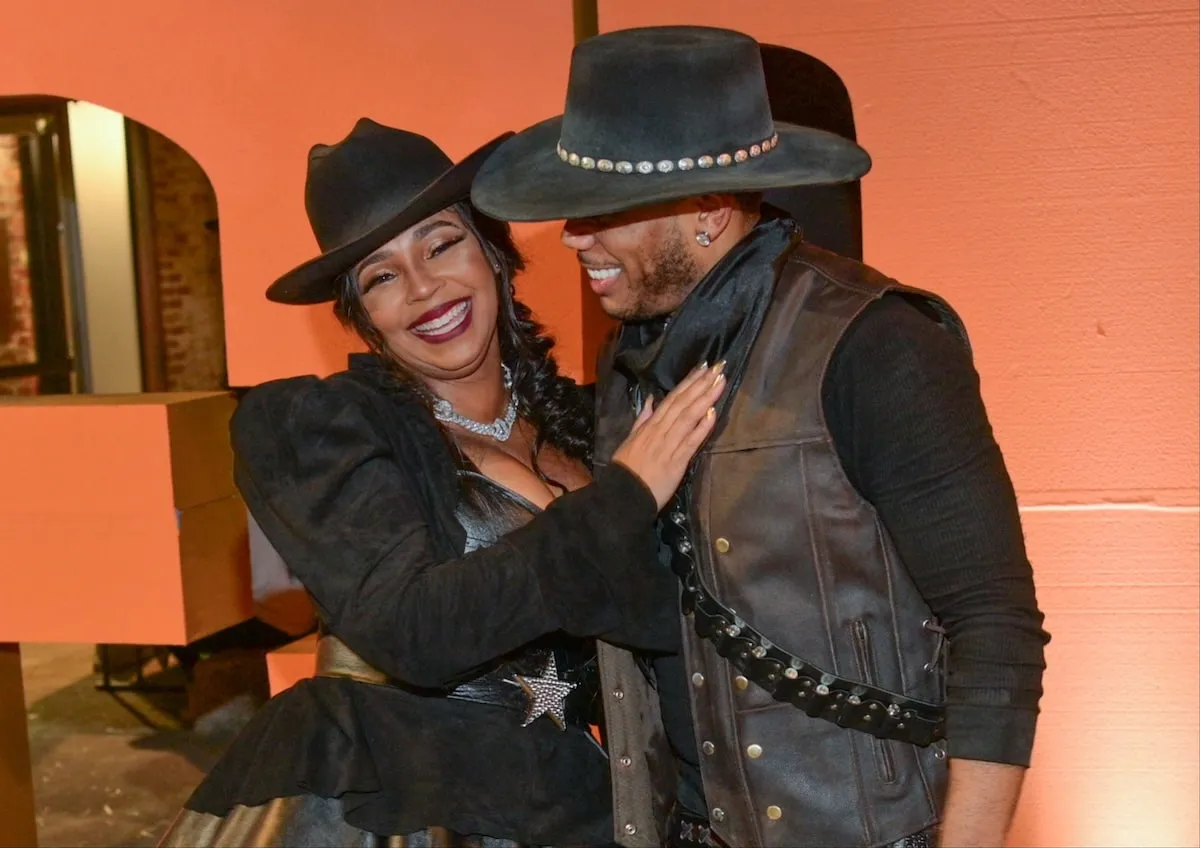 Wearing black cowboy costumes, Nelly and Ashanti smile for a photo at their Halloween party