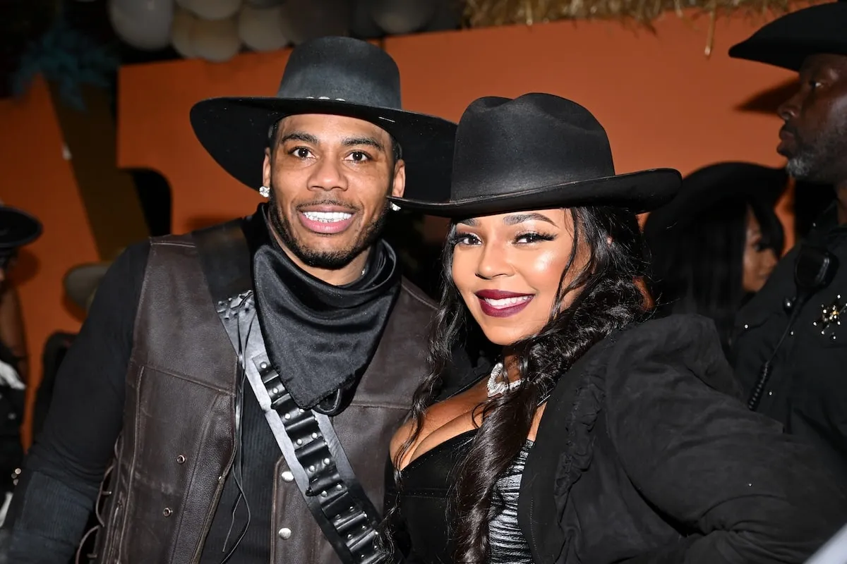 Wearing black cowboy costumes, Nelly and Ashanti smile for a photo at their Halloween party