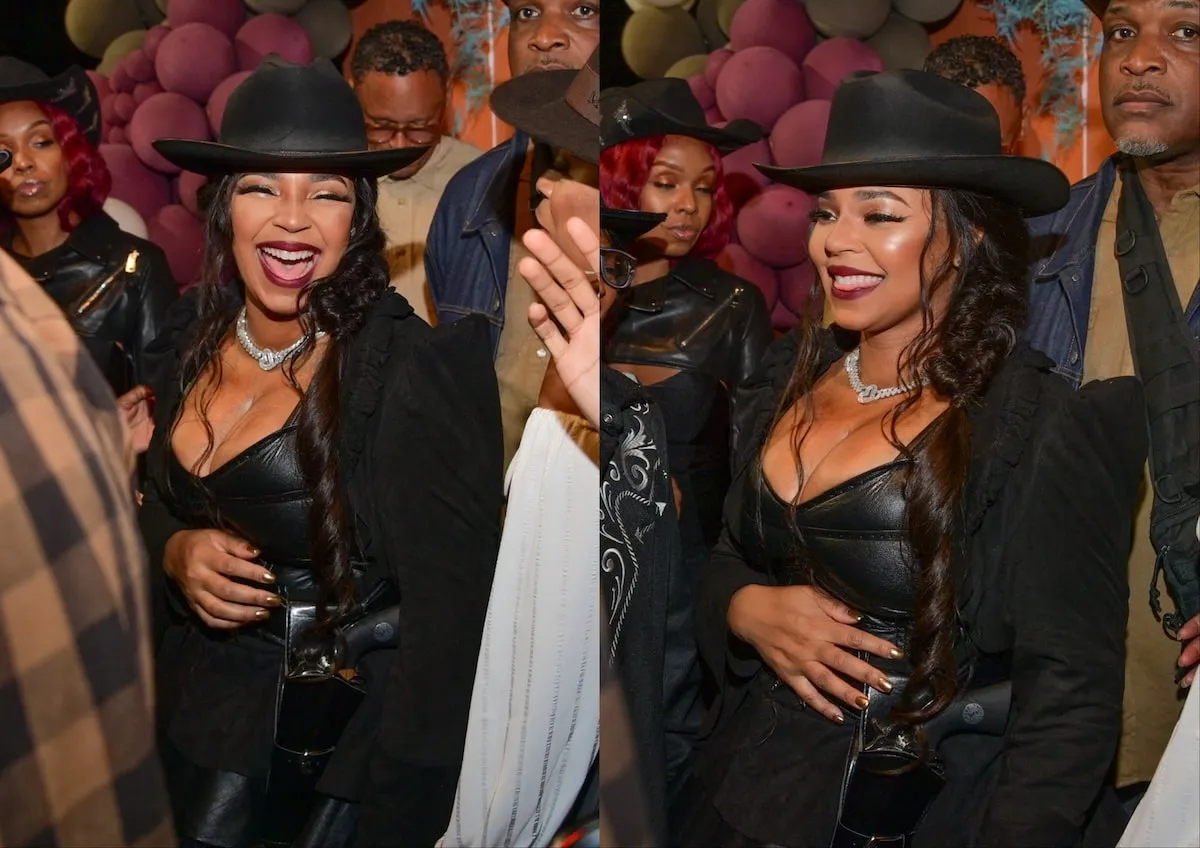 Wearing a black cowgirl costume, Ashanti smiles in front of hay bales Nelly's Halloween party and 50th birthday party