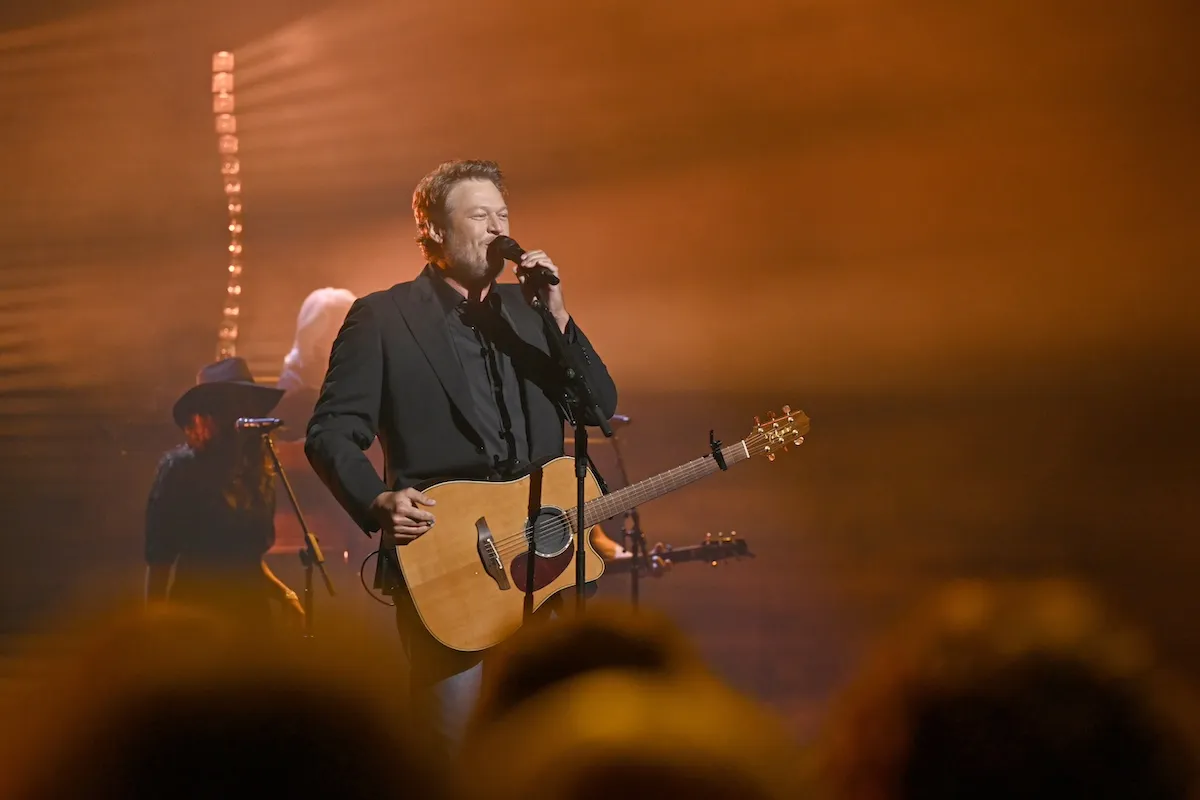 Blake Shelton holding a guitar and singing into a microphone