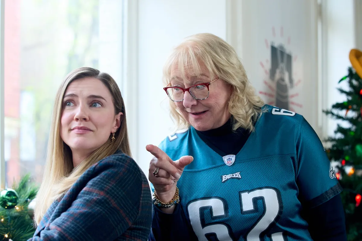 Donna Kelce, wearing an Eagles jersey, leans over Sara Canning's shoulder in the Hallmark Channel movie 'Christmas on Call'