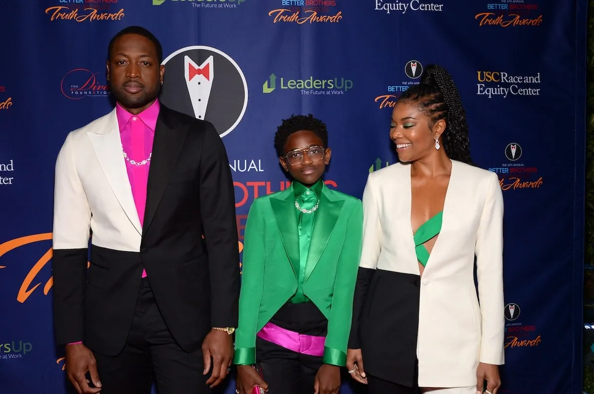 Wearing complimentary white, green, black, and pink tuxedos, Dwyane Wade, Zaya Wade, and Gabrielle Union pose on the red carpet in 2020