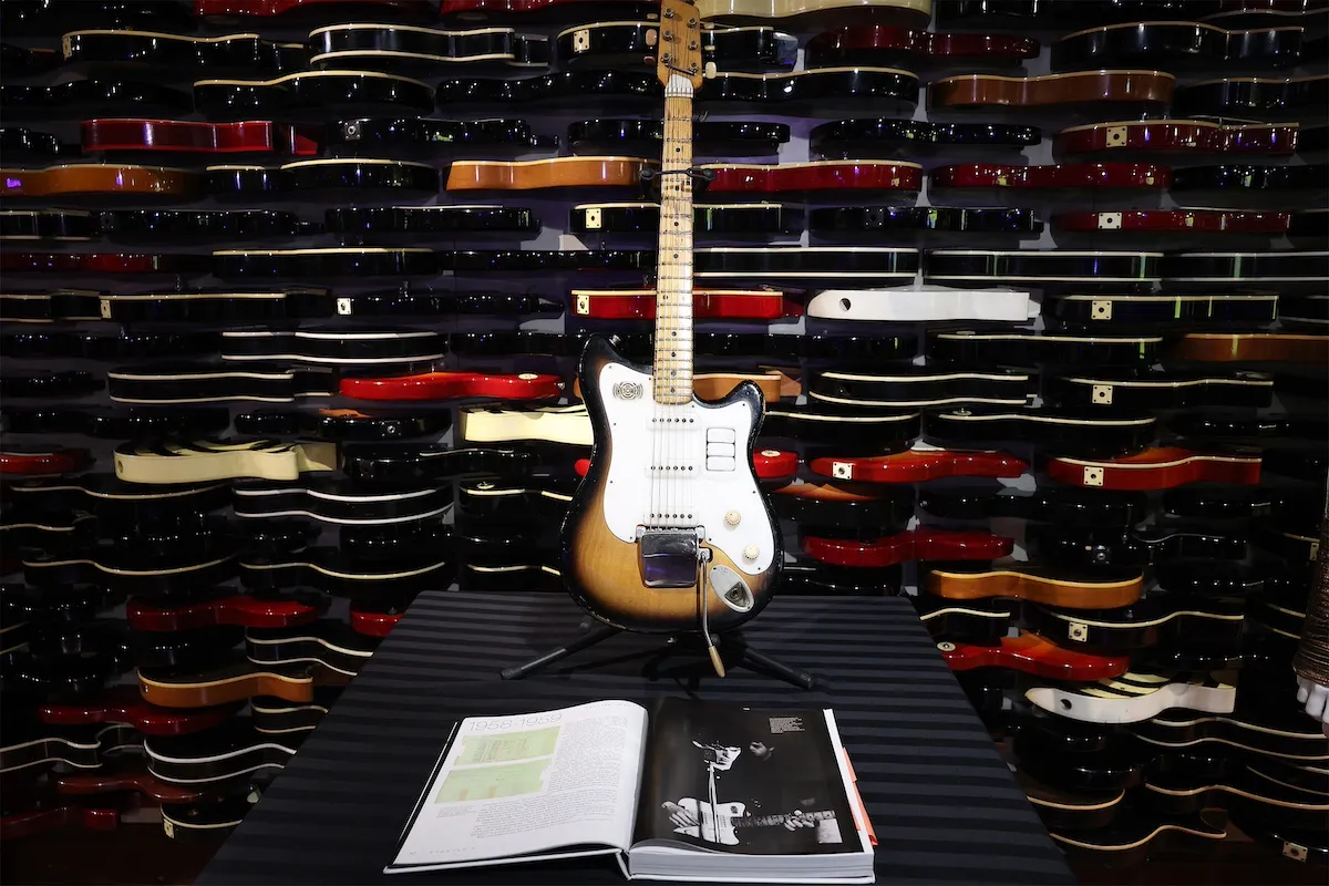 George Harrison's Futurama guitar displayed in front of a wall of other horizontal guitars