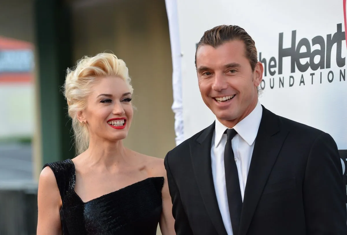 Gwen Stefani and Gavin Rossdale stand together. She wears a black dress and he wears a suit.