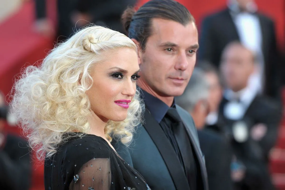 Gwen Stefani wears a black dress and stands with Gavin Rossdale, who wears a black suit.