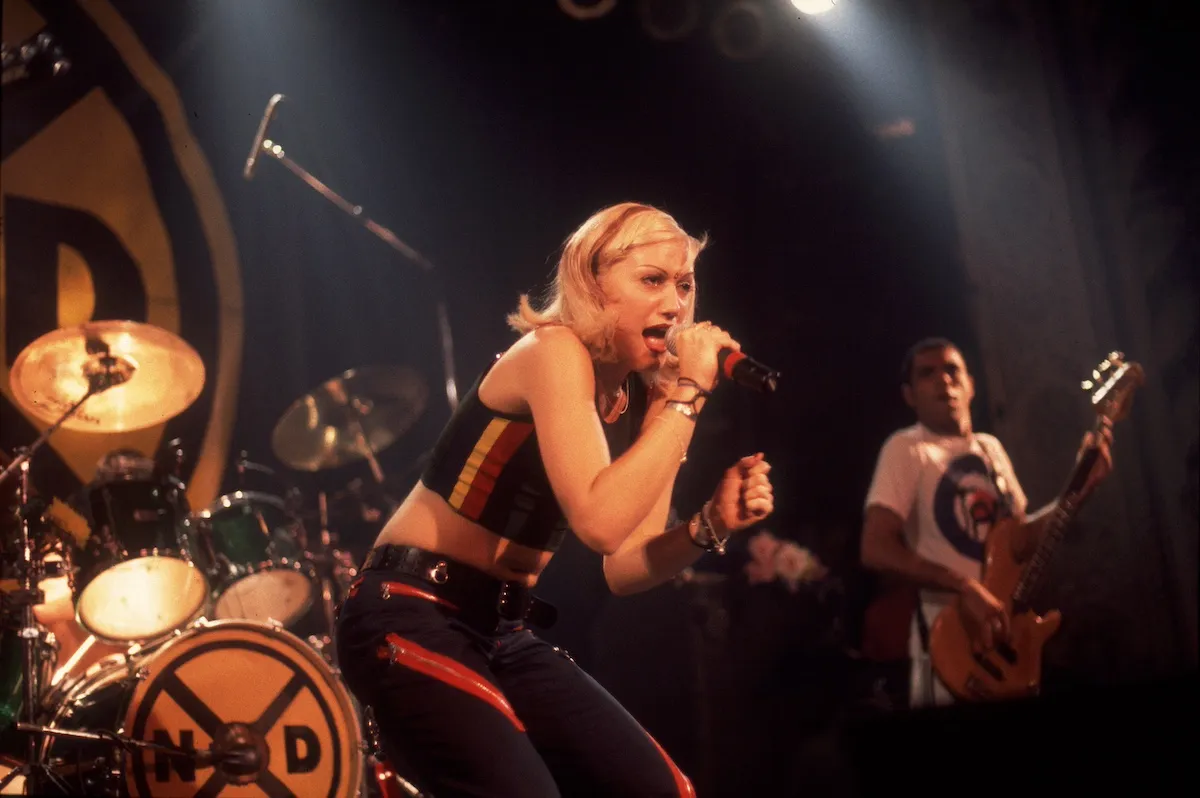 Gwen Stefani sings into a microphone while on stage with No Doubt in 1996