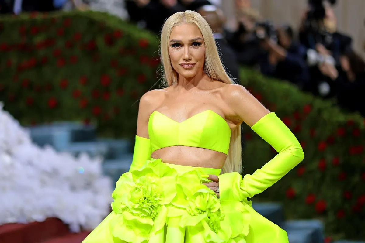 Gwen Stefani wears a neon green skirt, bralette, and sleeves. She stands with her hand on her hip.