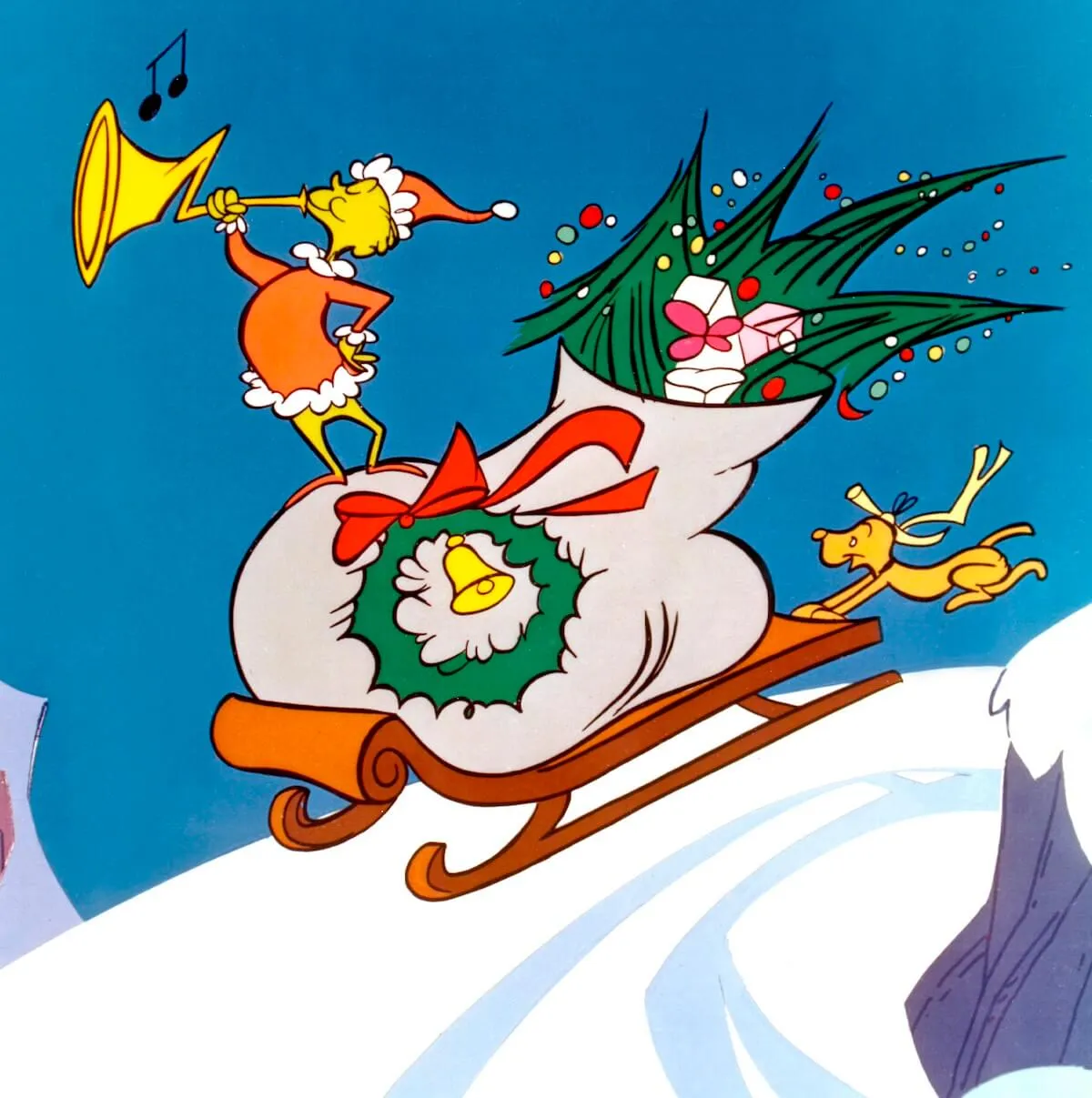 The Grinch sliding down a snowbank on a sled while standing on top of an over-stuffed sack from the 1966 animated special 'How the Grinch Stole Christmas'