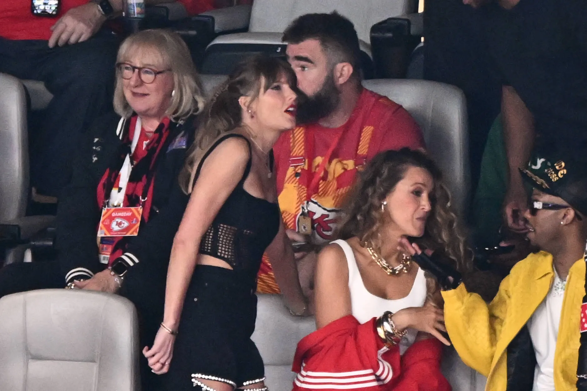 Jason Kelce closely speaking into Taylor Swift's ear at the Super Bowl. They're next to Donna Kelce and others in the stands.