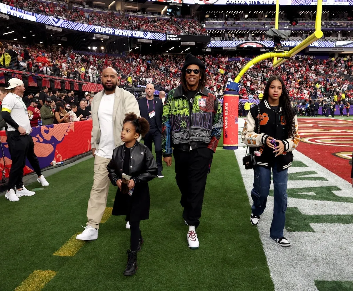 Rumi Carter, Jay-Z, and Blue Ivy Carter walk on the sideline of Super Bowl LVIII