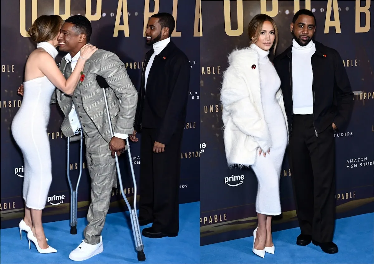 Wearing a white coat and white sweater dress, Jennifer Lopez poses with costars, Anthony Robles and Jharrel Jerome, on the red carpet before the UK premiere of 'Unstoppable'