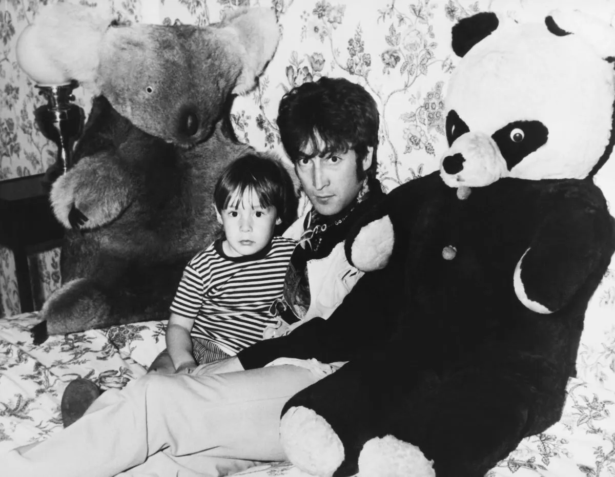 A black and white picture of Julian Lennon and John Lennon sitting between a large stuffed koala and stuffed panda.