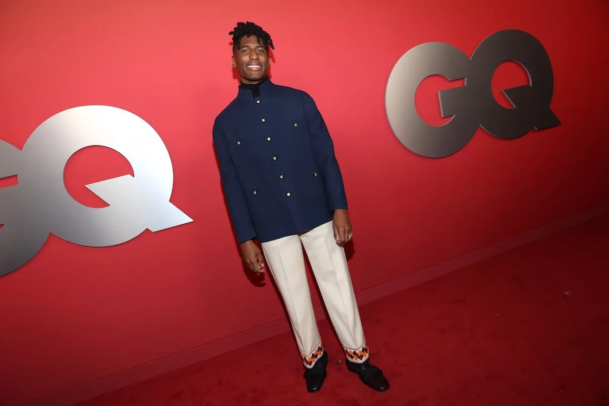 Wearing a blue jacket and white pants, Jon Batiste poses for photos on the red carpet at the 2024 GQ Men Of The Year Party