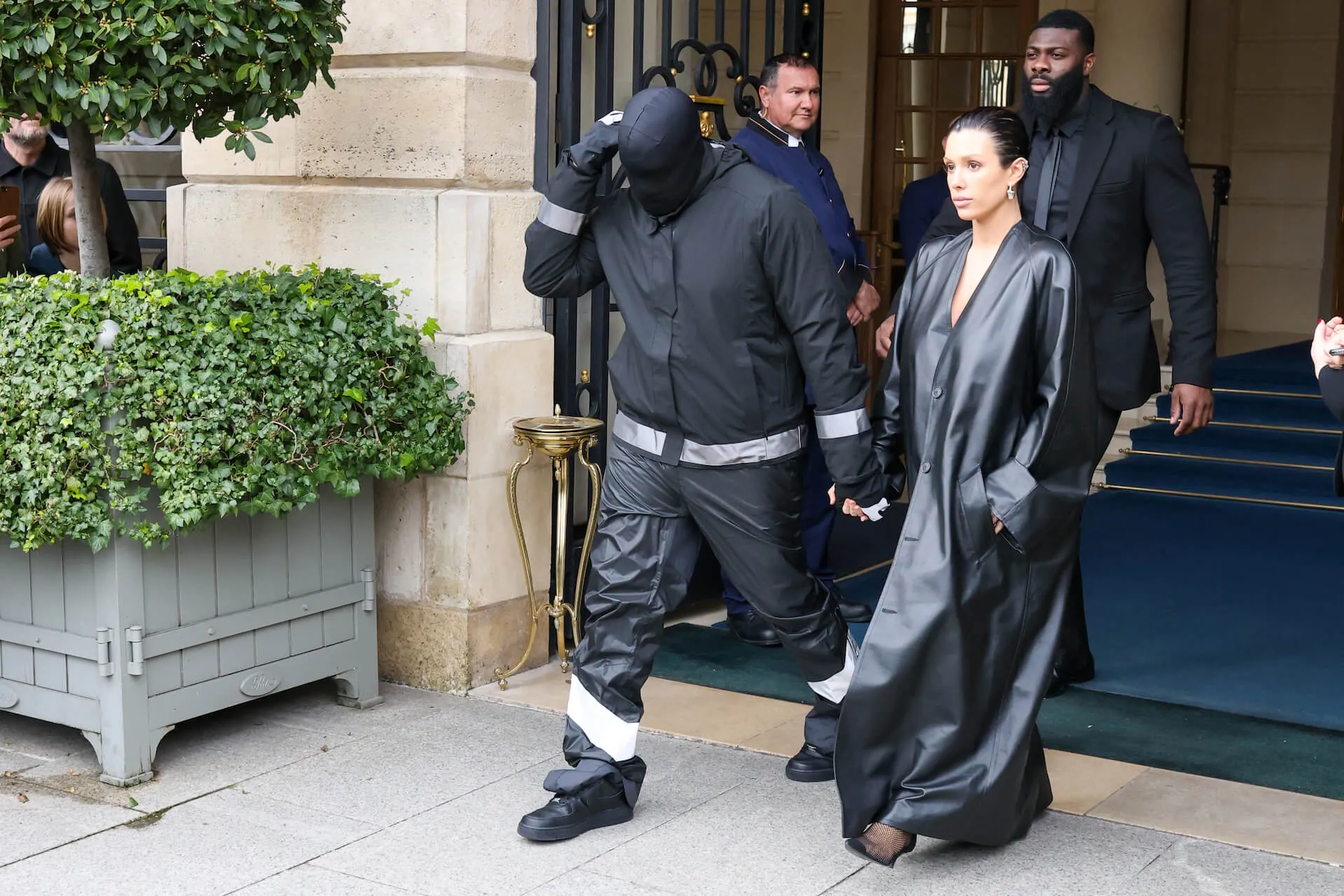 Kanye West and Bianca Censori are seen leaving their hotel on Feb. 28, 2024, in Paris, France. West is wearing all black with a black hood over his face. Censori is wearing a black floor-length coat.