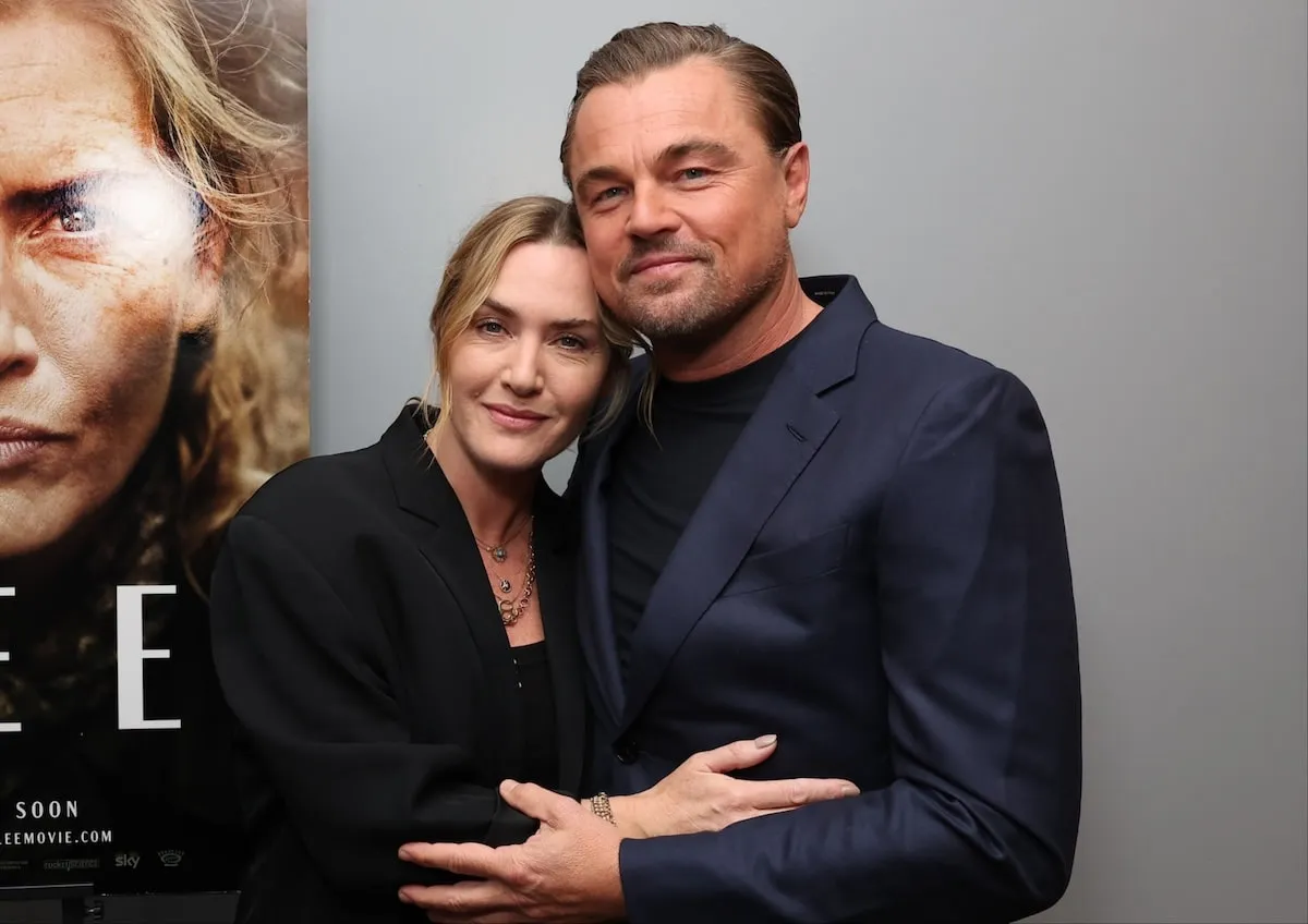 Embracing each other, Kate Winslet and Leonardo DiCaprio pose next to a poster for Winslet's 2024 film, 'Lee'