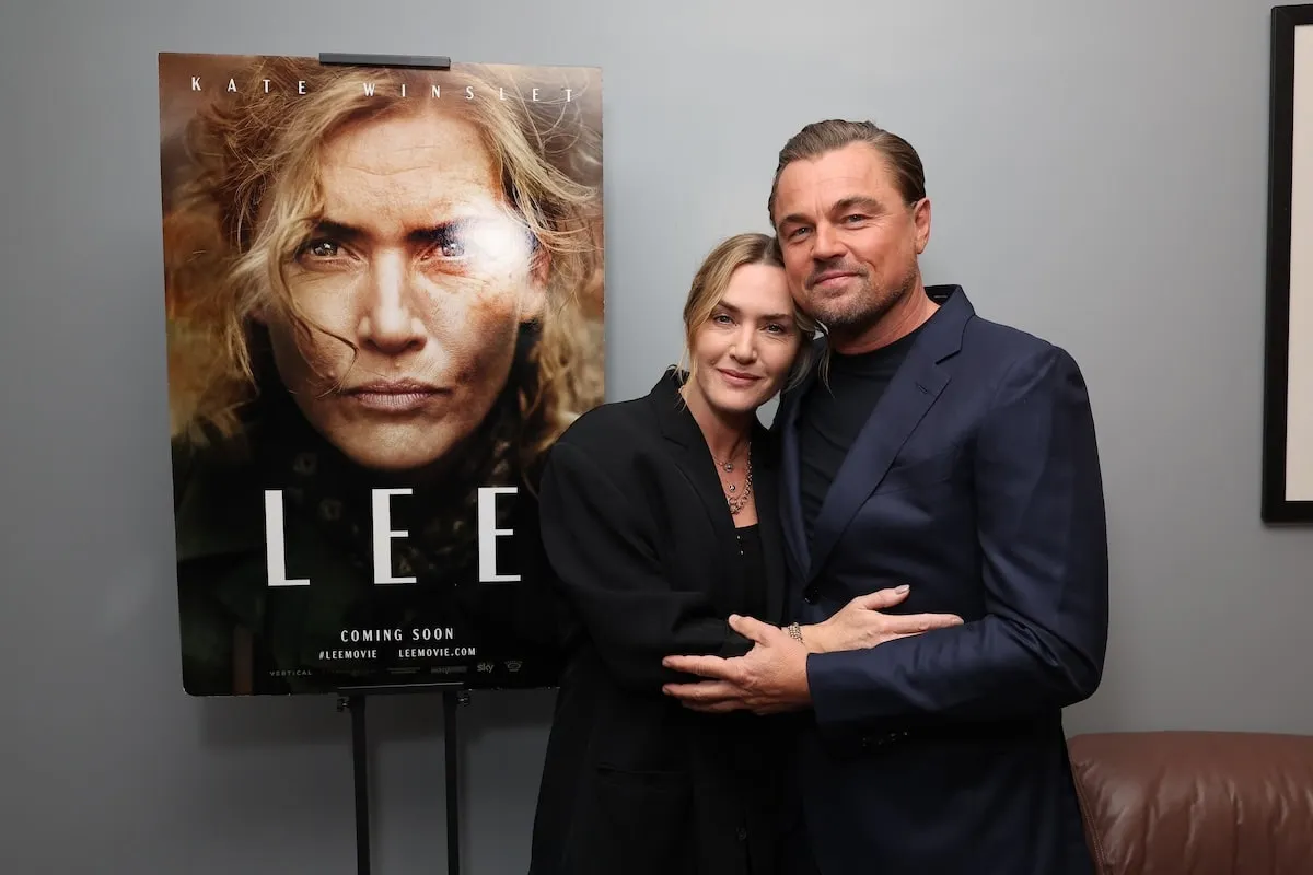 Embracing each other, Kate Winslet and Leonardo DiCaprio pose next to a poster for Winslet's 2024 film, 'Lee'