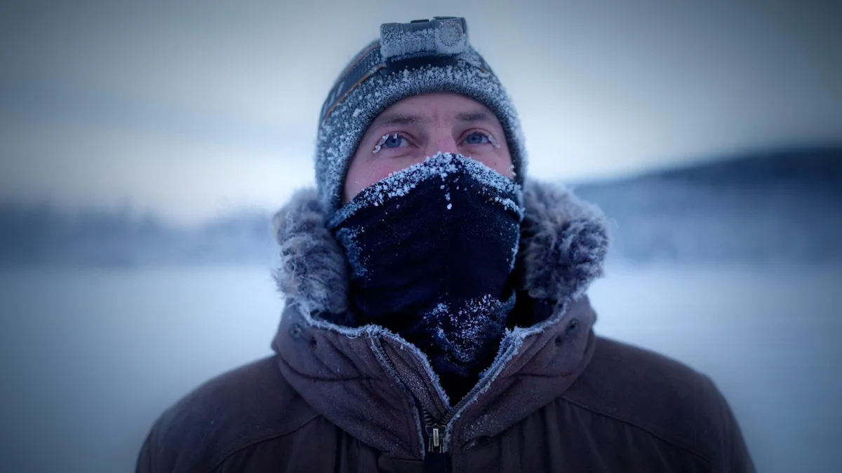 Man wearing a hat and scarf that are dusted with snow in 'Life Below Zero'