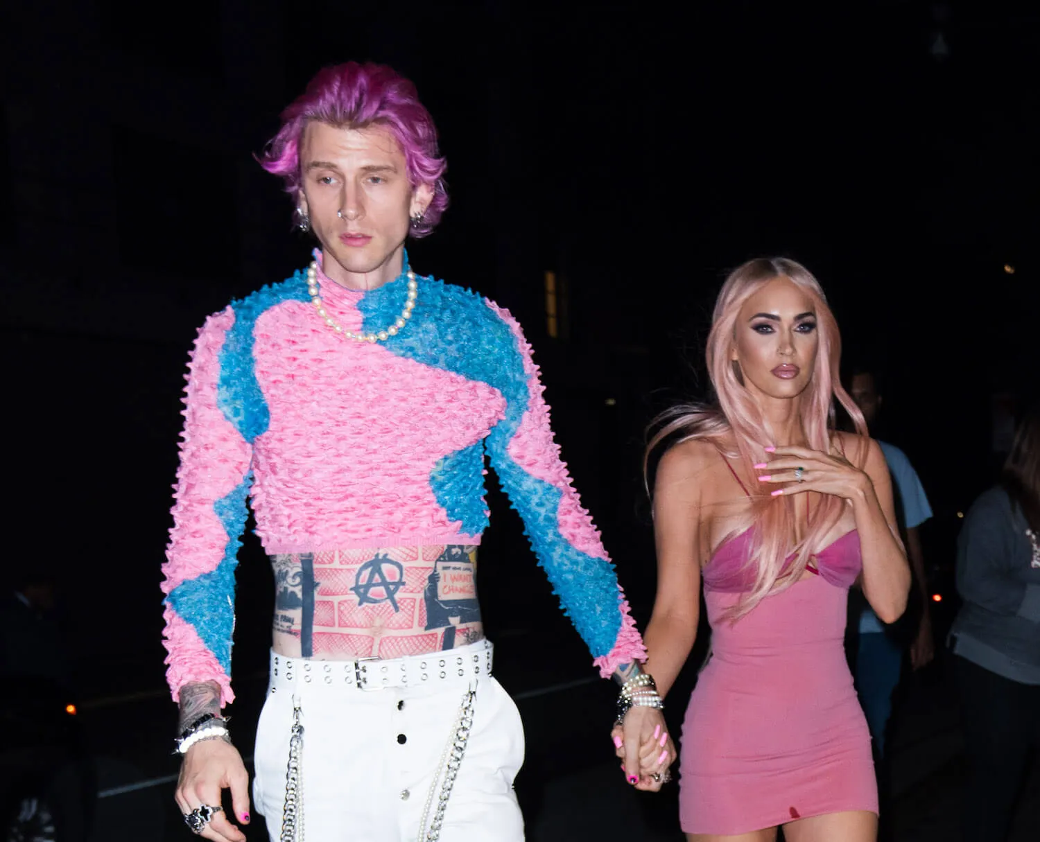 Machine Gun Kelly and Megan Fox walking at night in New York City. They are both wearing pink outfits.