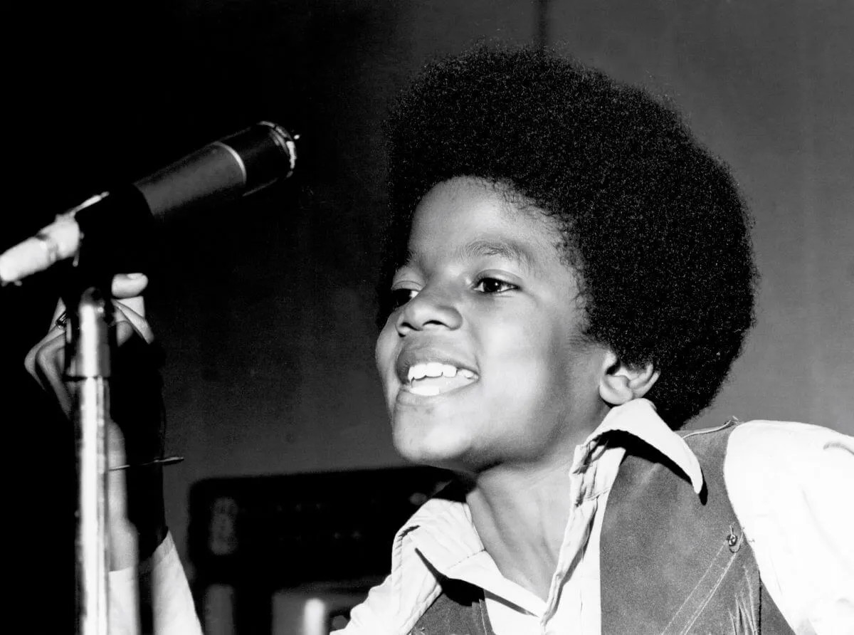 A black and white picture of a young Michael Jackson standing in front of a microphone.