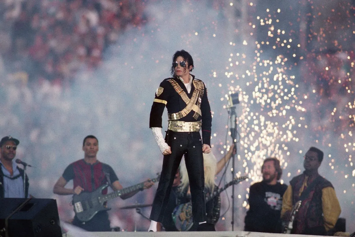 Michael Jackson stands on a stage. Sparks fly around him.