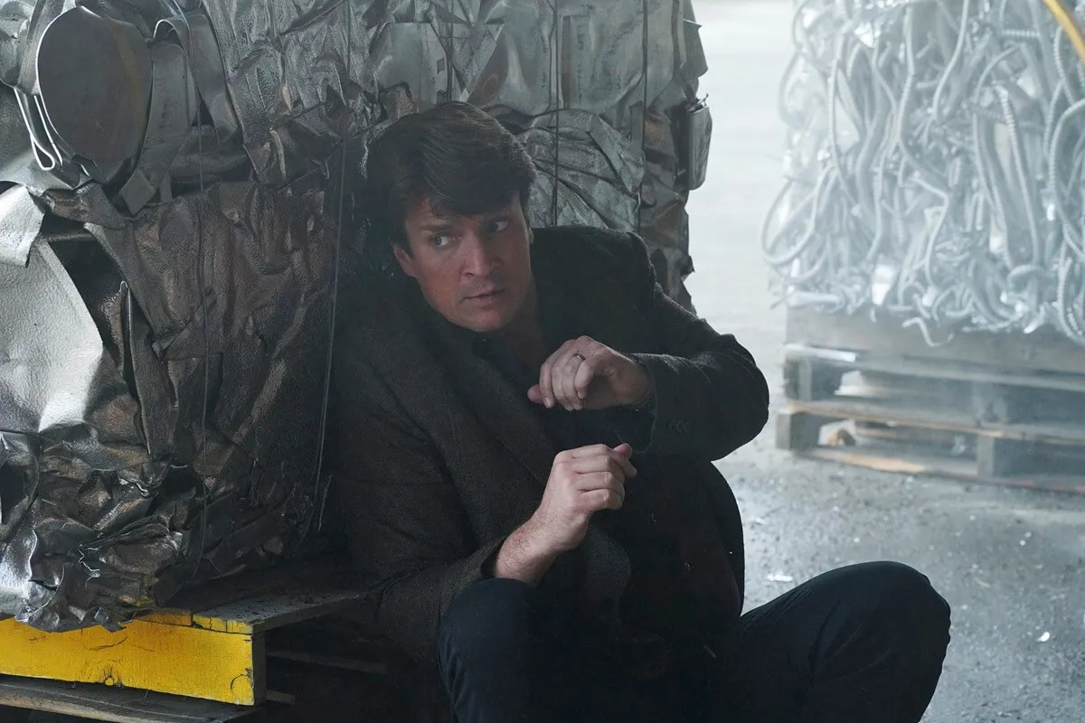 Nathan Fillion taking cover while playing Richard Castle in an episode of 'Castle'.