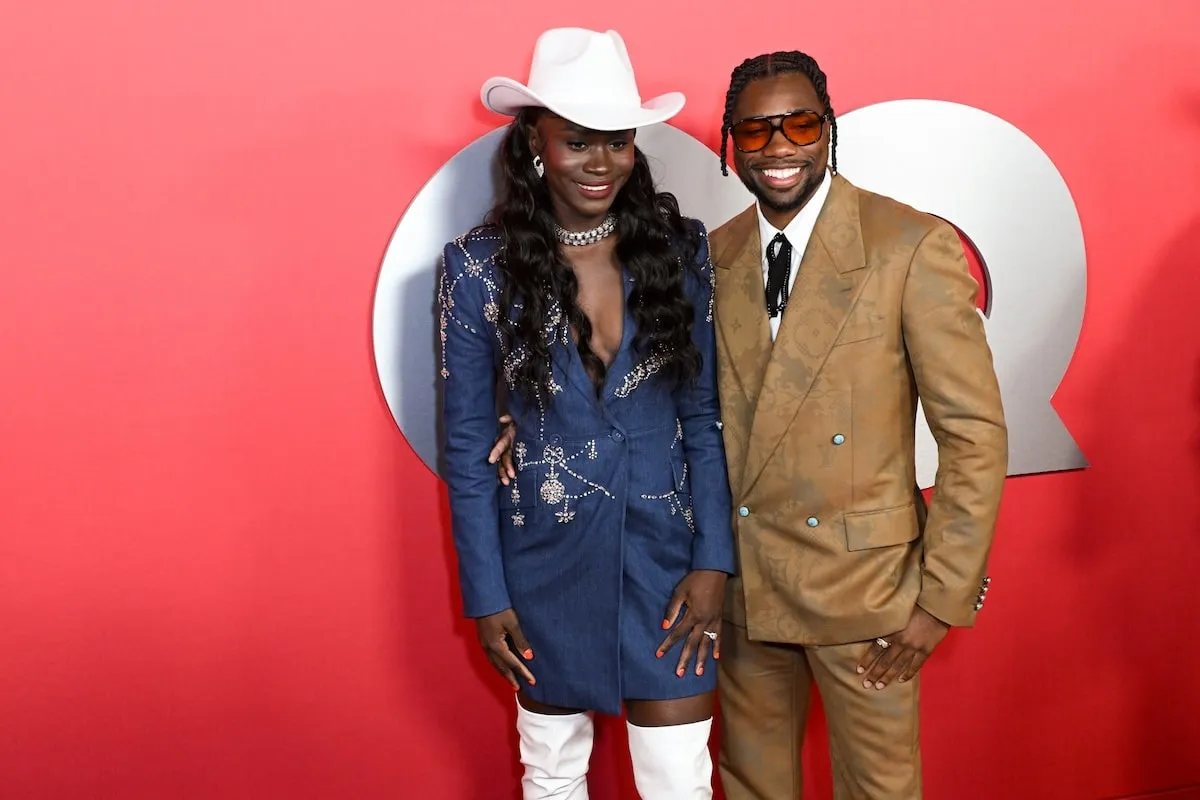 Wearing a tan suit set, Noah Lyles poses with girlfriend Junelle Bromfield for photos on the red carpet at the 2024 GQ Men Of The Year Party