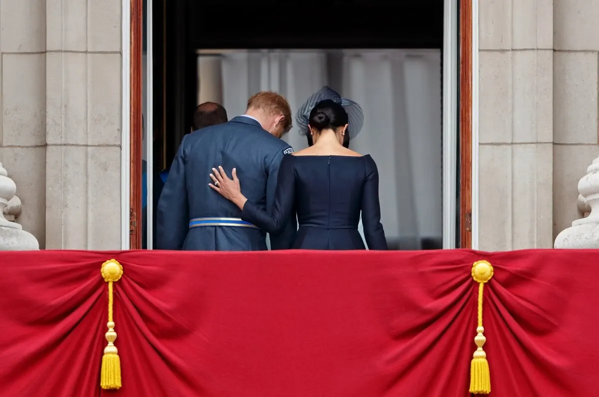 Prince Harry and Meghan Markle walk back inside Buckingham Palace after watching a flypast to mark the centenary of the Royal Air Force