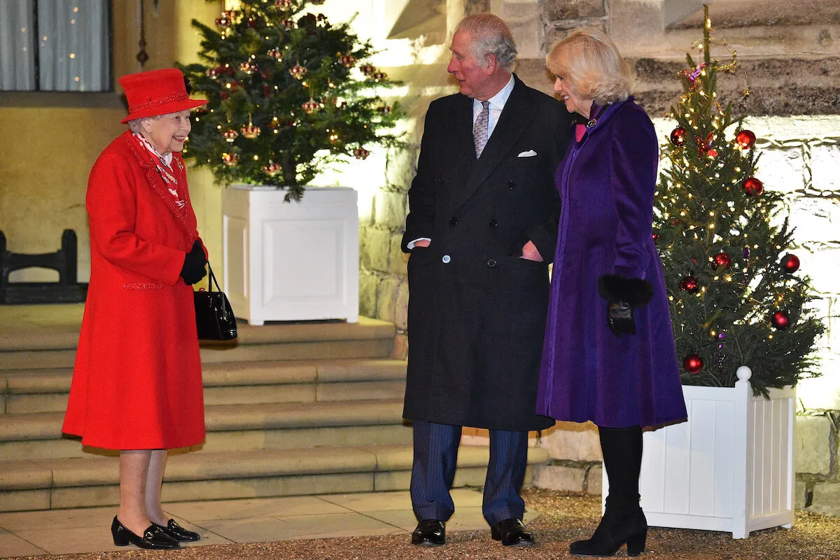 Queen Elizabeth II, King Charles III, and Queen Camilla stand next to a Christmas tree. 