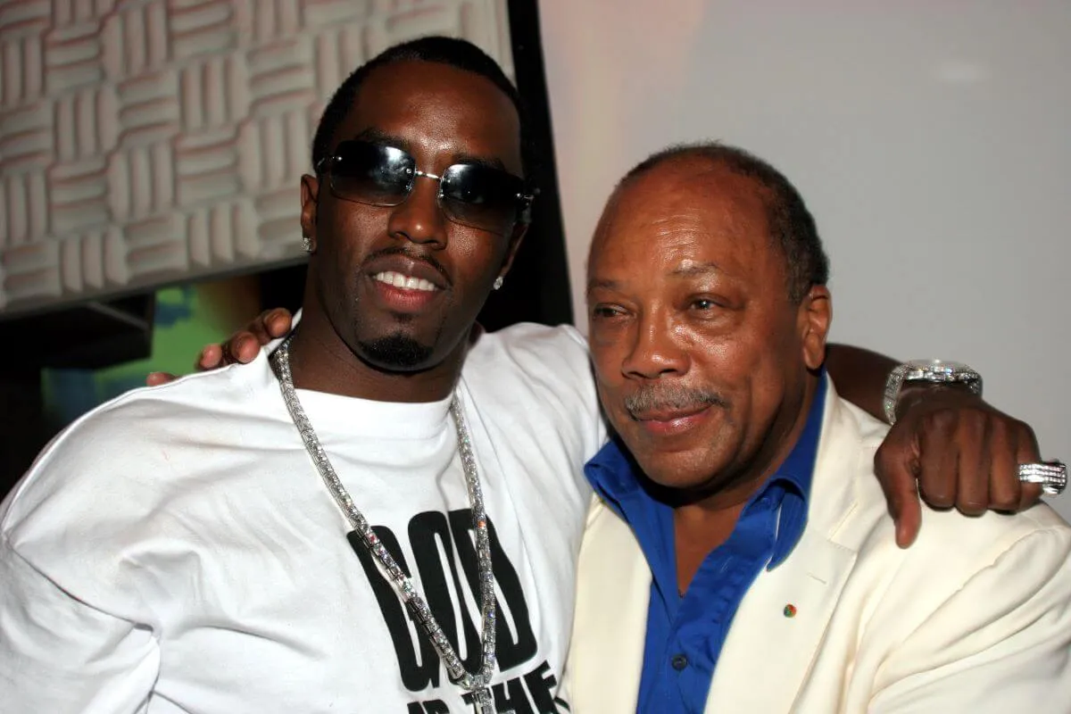 Sean 'Diddy' Combs stands with his arm around Quincy Jones' shoulders. He wears a white shirt and sunglasses and Jones wears a white jacket and blue shirt.