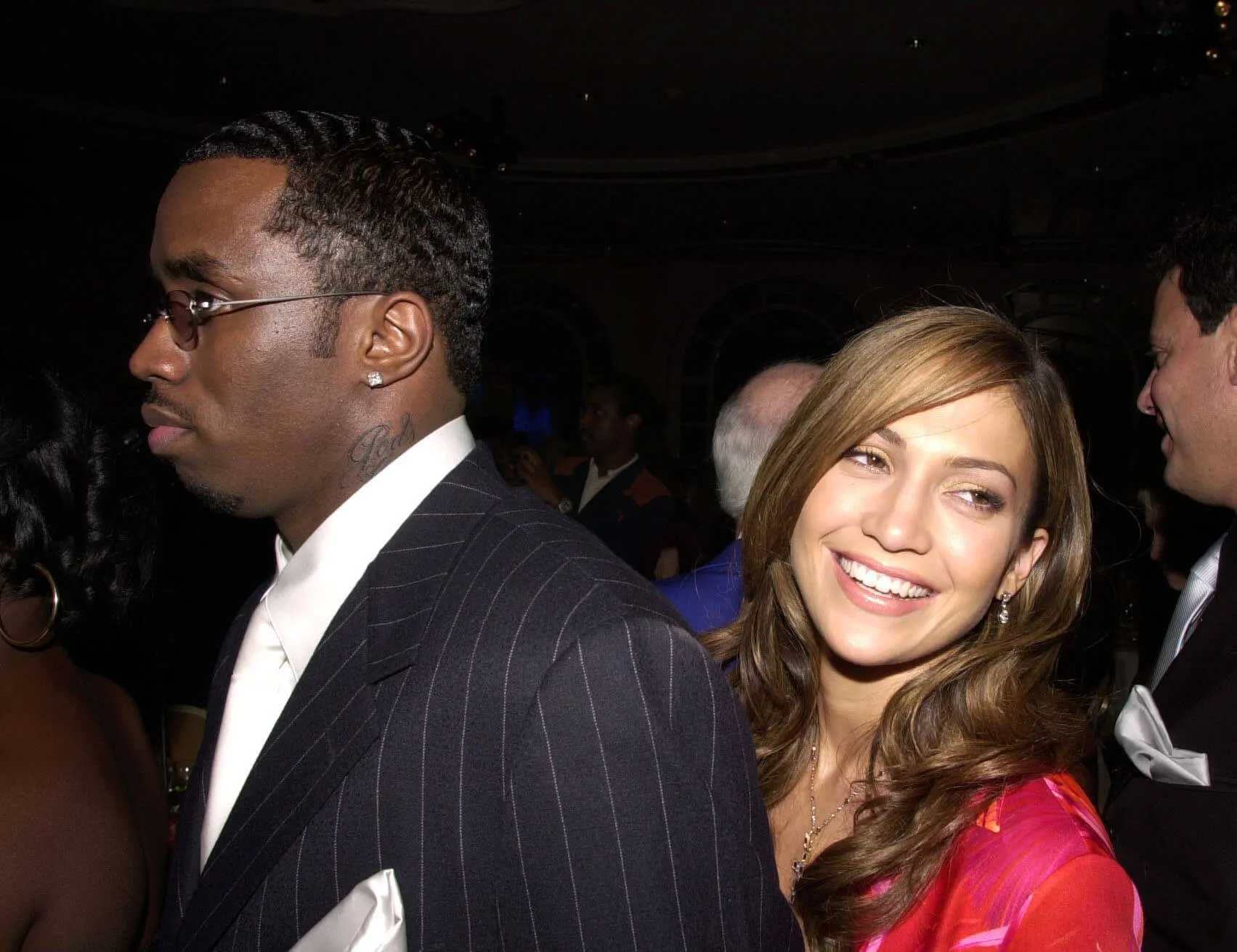 Sean 'Diddy' Combs walking in front of Jennifer Lopez. Lopez is smiling and looking over her shoulder.