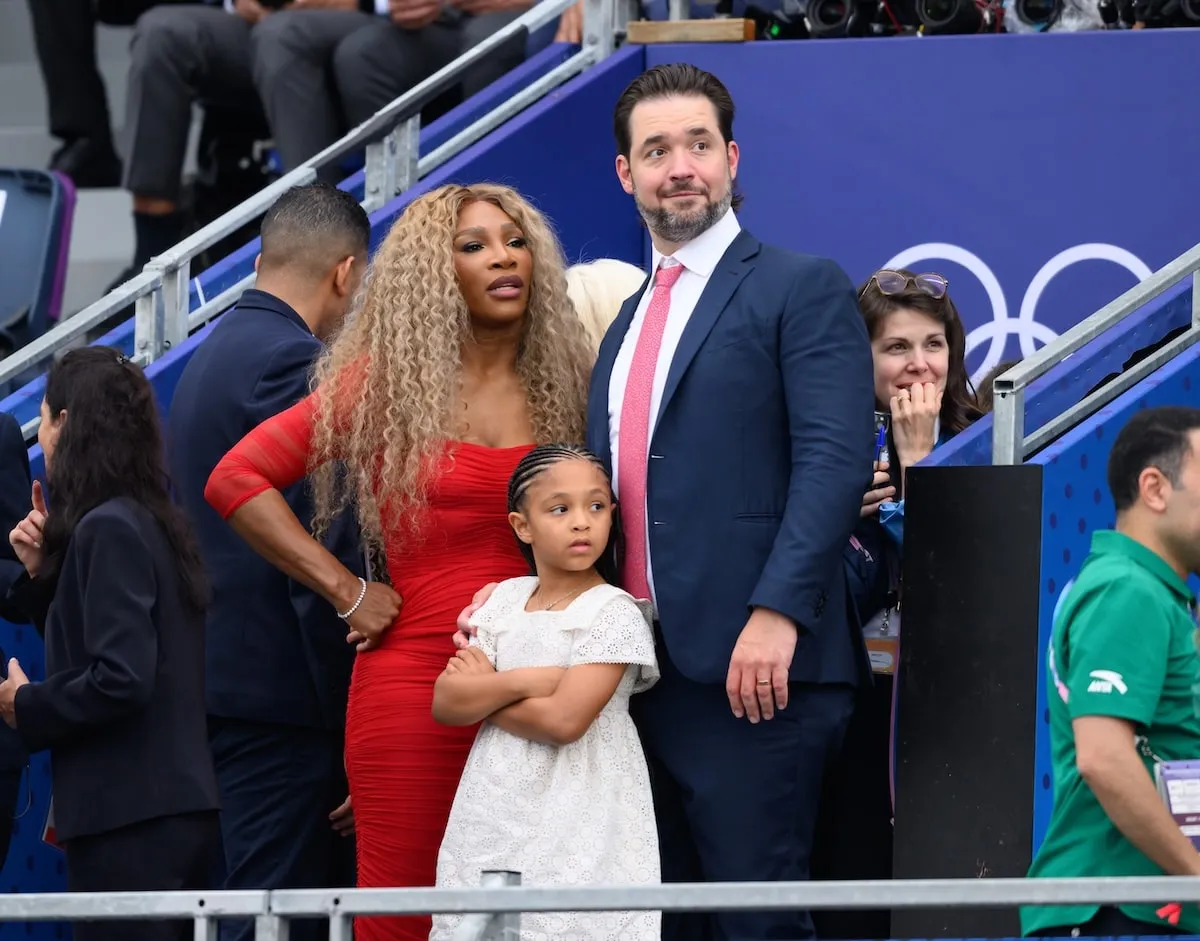 Wearing a red dress, Serena Williams, Alexis Ohanian, and their daughter Adira River attend the Opening Ceremony of the Olympic Games Paris 2024