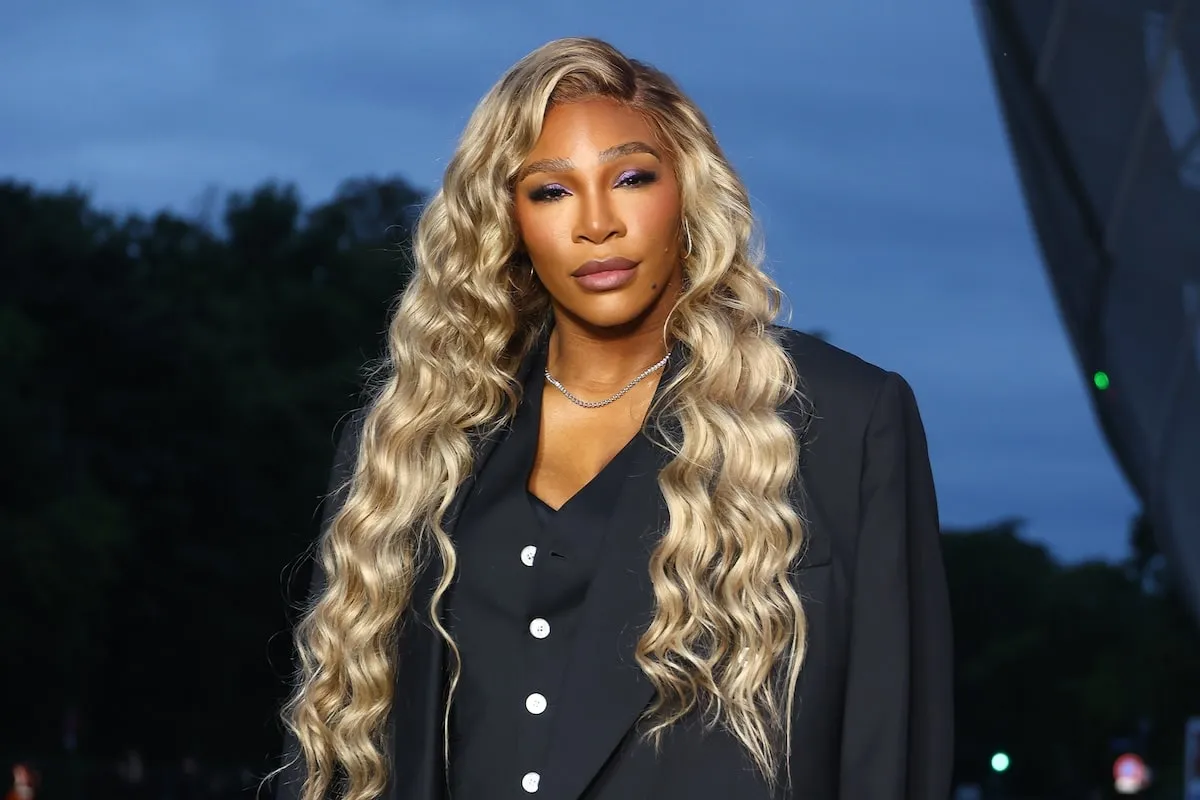 Wearing a black blazer and pants, Serena Williams smiles outside of the Prelude to The Paris Games 2024